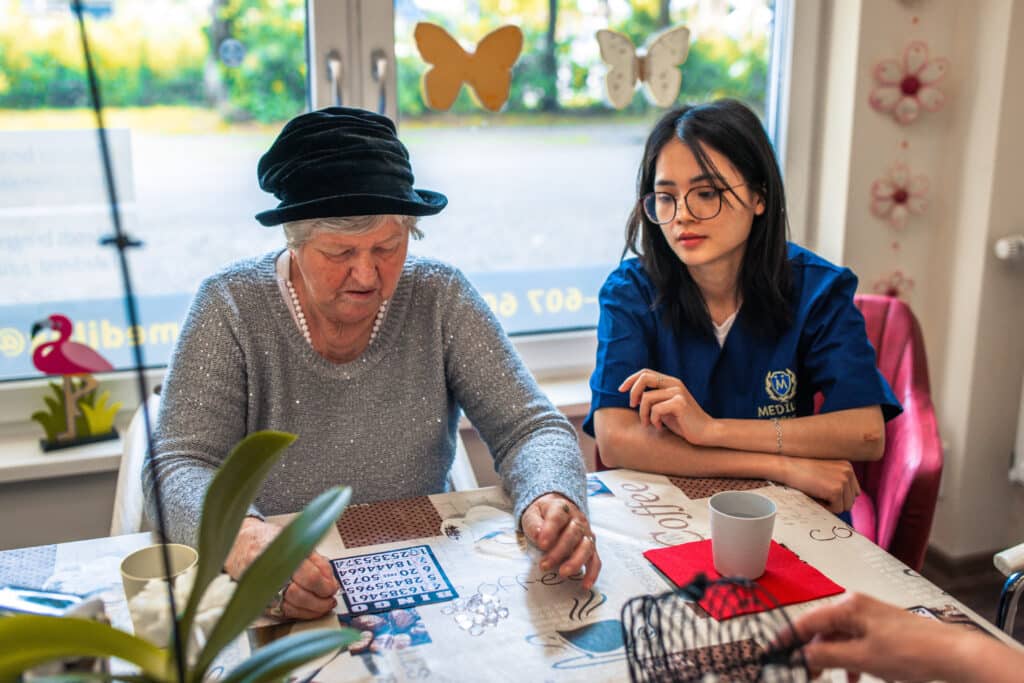 Moderne Pflegekonzepte - Wie innovative Ansätze den Lebensabend bereichern 1 Pflegerin spielt ein Brettspiel mit einer Bewohnerin