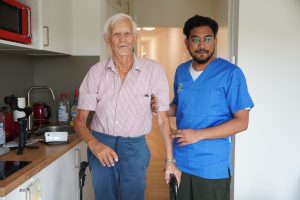 Bewohner und Pflegekraft in der eigenen Wohnung mit Küchenzeile